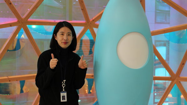 a person standing next to a blue rocket statue